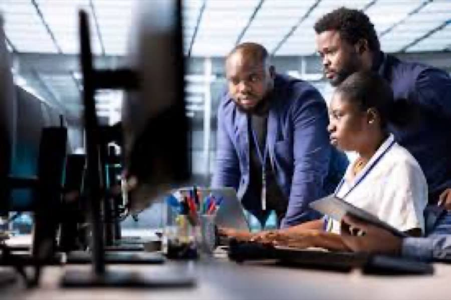 Diverse team of professionals collaborating around a desk while reviewing work on a screen