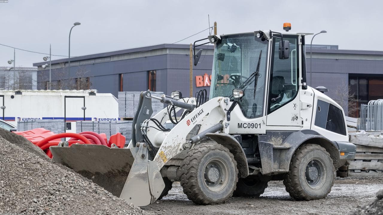 A wheel loader working a construction site with staged materials in the background