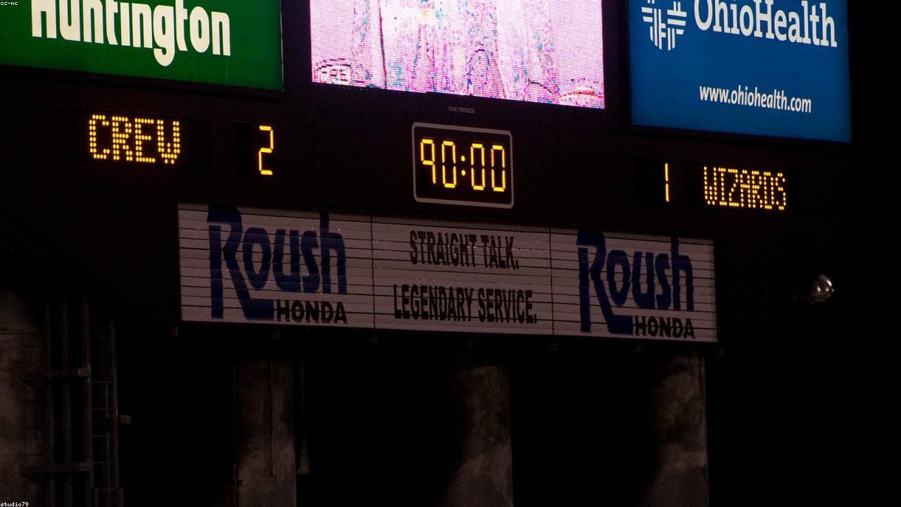 A soccer stadium scoreboard reading 90:00 at full time under stadium lights